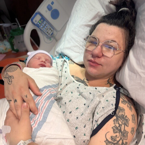 mother in hospital gown holding newborn baby