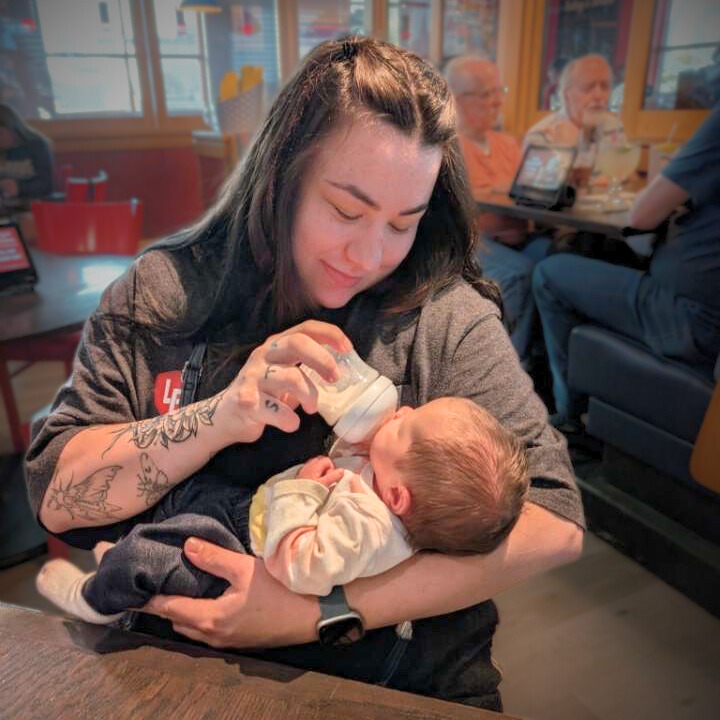 birth mother feeding bottle to newborn baby