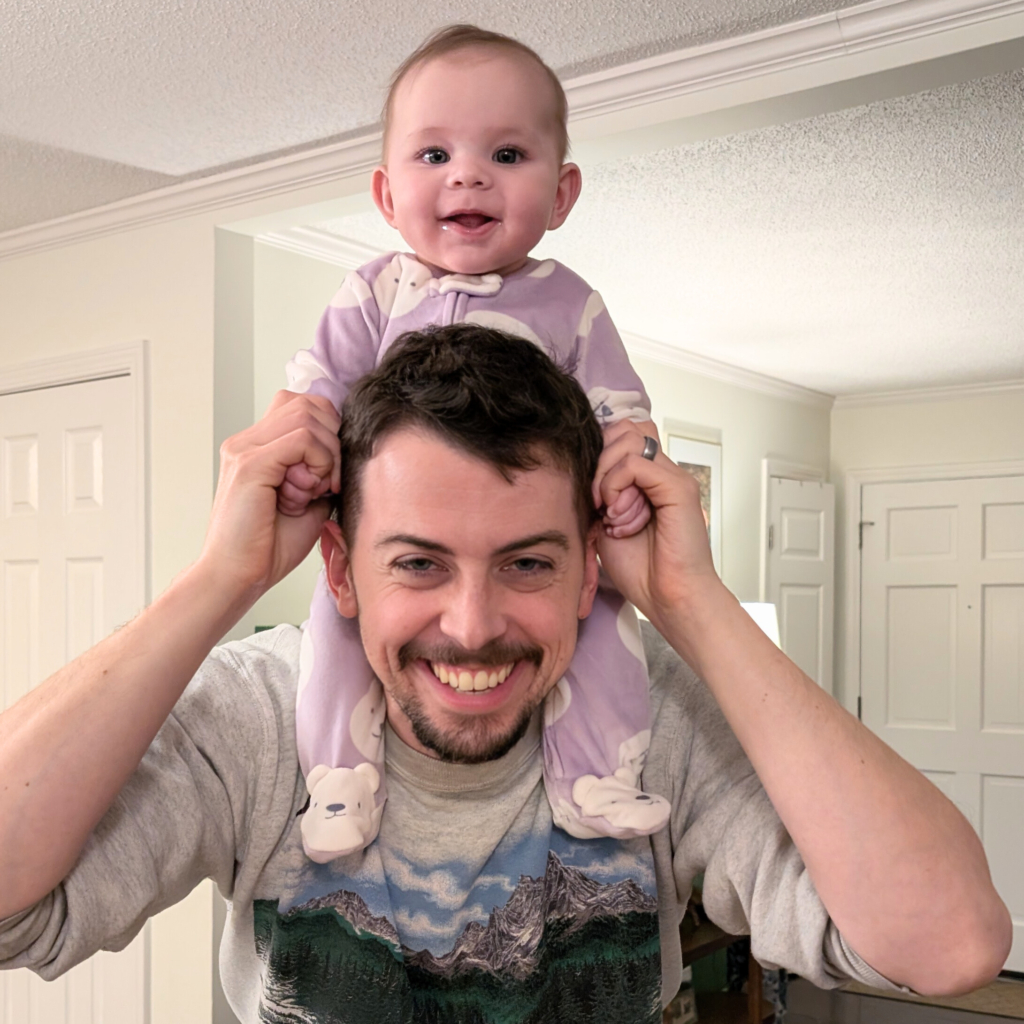 Father with baby daughter on shoulders.