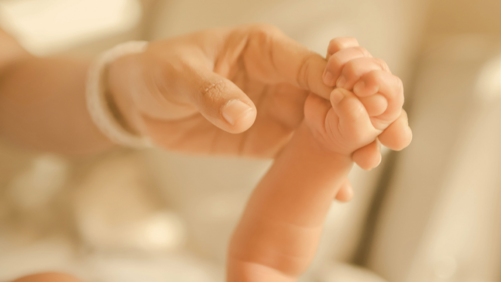woman holding baby's hand