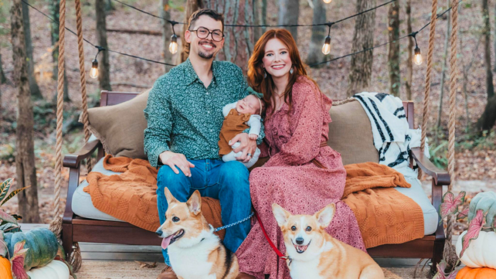 Family sitting mother and father with baby and two dogs.