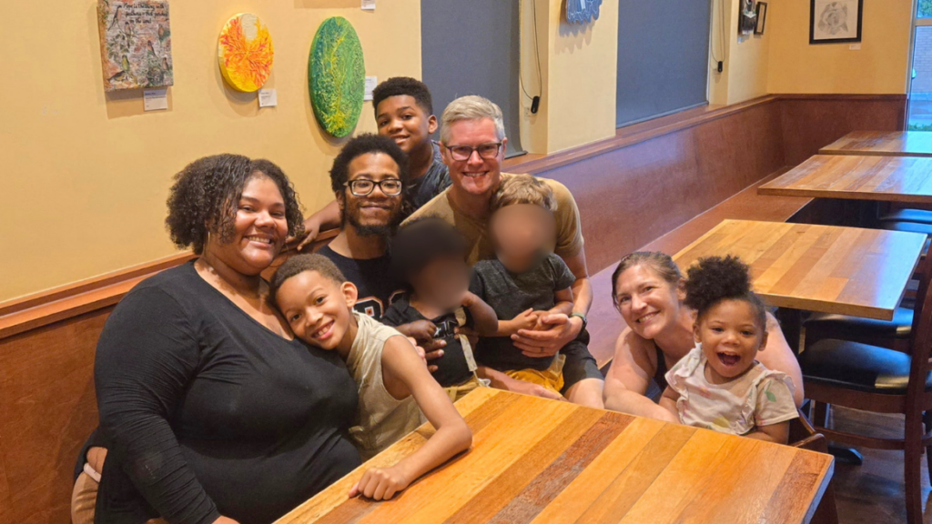 four adults and four children sitting around a table